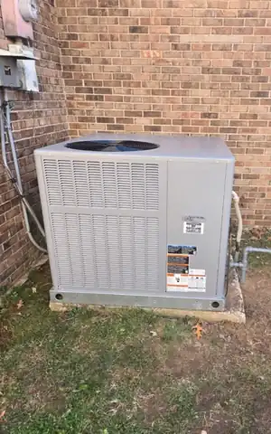 A packaged unit set against a brick wall on a pad.