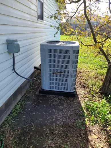 New condenser set on a pad along vinyl siding
