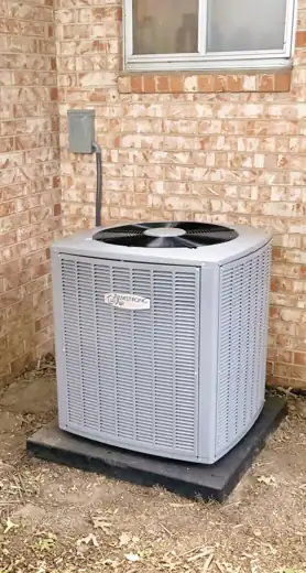 Armstrong Air condenser on a new pad against a brick wall