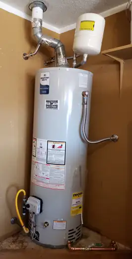 A tank water heater in a closet, carrying their Masters of Disasters sticker.