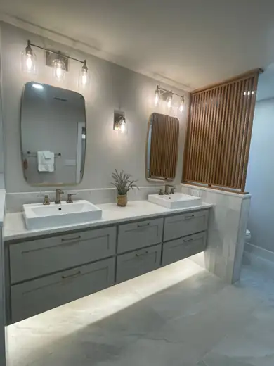 A floating double vanity with a wood slat screen and sconces.