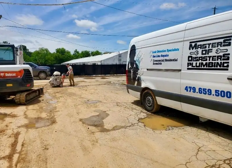 The Masters of Disasters plumbing van parked beside a mini excavator on a job site